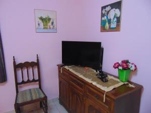 telewizor siedzący na komodzie z krzesłem w obiekcie Nasos's Country House w mieście Porto Rafti