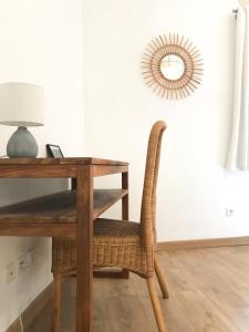 een houten tafel met een rieten stoel naast een bureau bij La Maison bleue in Arles