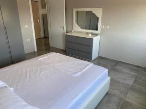 um quarto com uma cama branca e um espelho em Emma's Apartments em Tirana