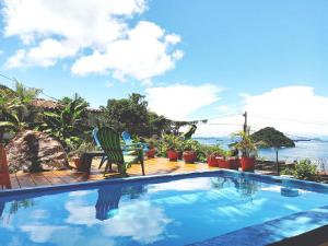 a swimming pool with two chairs and the ocean at Cerrito Tropical Eco Lodge in Taboga