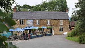 un edificio di mattoni con persone sedute fuori di Osprey Cottage, Manton in Rutland a Manton