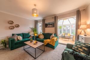 a living room with green couches and a table at Luxury Southampton house with garden and parking in Southampton