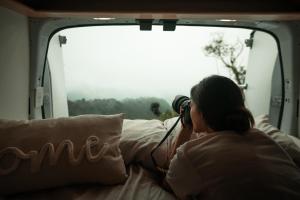 聖胡安的住宿－Vive La Van，一位女士在野营车里用相机拍照片