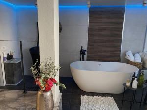 een badkamer met een wit bad en een vaas met bloemen bij daniela in Eilat
