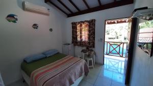 een slaapkamer met een bed en een groot raam bij Curral Beach in Ilhabela