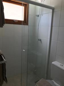 a glass shower in a bathroom with a toilet at Pousada OAK Plaza in Monte Verde
