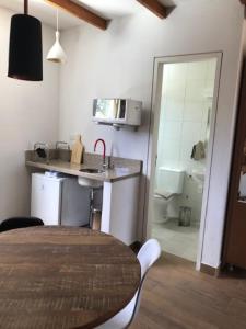 a kitchen with a table and a sink and a bathroom at Pousada OAK Plaza in Monte Verde