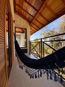 a hammock on the balcony of a house at Refúgio Physis Suítes in Monte Verde