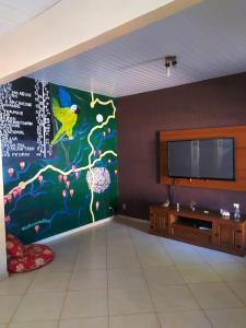 a living room with a tv and a mural on the wall at Conexão Hostel in Alto Paraíso de Goiás