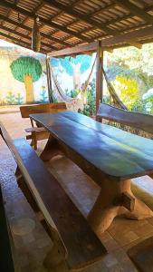 a large wooden picnic table in a room with hammocks at Conexão Hostel in Alto Paraíso de Goiás