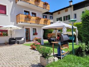 "Casa Elda" 110 mq primo Piano a Coredo TRENTO في كوريدو: شخص يجلس على طاولة تحت مظلة