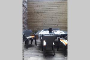 a table and chairs on a patio with a brick wall at Maison de pêcheur près du port in Étaples