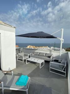 een patio met een parasol en banken op een dak bij Luxury Penthouse Pedro - The View Fuengirola in Fuengirola