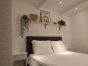 a bedroom with a bed with white sheets and plants at KDF Apartments in Willemstad