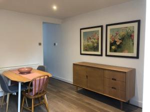 a dining room with a table and a cabinet and two paintings at Boutique City Centre Home in Chichester +10 photos