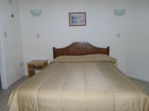 Schlafzimmer mit einem großen Bett mit einem Kopfteil aus Holz in der Unterkunft Apart Hotel Fx in Puerto Montt