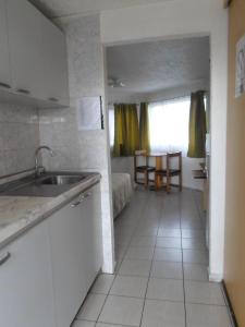 uma cozinha com um lavatório e um quarto com uma mesa em Apart Hotel Fx em Puerto Montt
