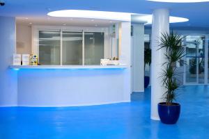a lobby with a counter with a plant in the middle at Apartamentos Bora Bora - Adults Only in Playa d'en Bossa