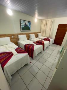 Una fila de cuatro camas en una habitación en Noronha Good Vibes Hostel, en Fernando de Noronha