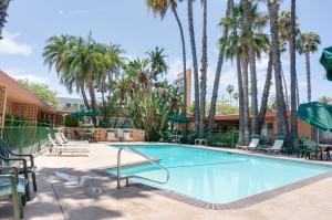 
a beach with a pool, chairs, and a pool table at Saga Motor Hotel Pasadena in Pasadena

