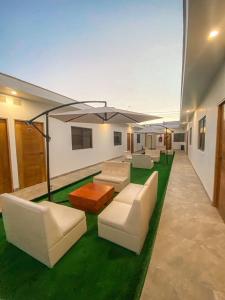 Nakua Paracas Lodge في باراكاس: غرفة معيشة مع أثاث أبيض وعشب أخضر