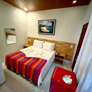 a bedroom with a large bed with a colorful blanket at Noronha Good Vibes Hostel in Fernando de Noronha