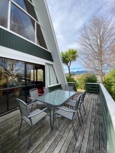 a patio with a glass table and chairs on a deck at 9 Chalet Cres in Hanmer Springs