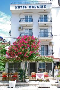 un hotel malete con flores rosas delante de él en Melaike Hotel, en Foca