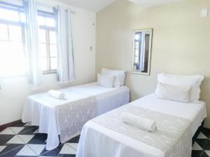 2 camas blancas en una habitación con ventanas en Viva Buzios, en Búzios