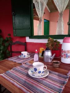 a wooden table with two cups and saucers on it at Chalés Encantos de Cunha Vermelho in Cunha