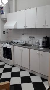 a kitchen with white cabinets and a black and white checkered floor at TANGO GUAPO APART in Buenos Aires