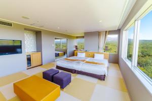 a bedroom with a bed and a tv and windows at Hotel Epinard Nasu in Nasu