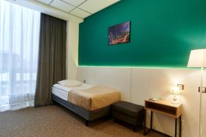 Habitación de hotel con cama y pared verde en Urban Hotel, en Omsk