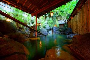 a pool of water in a room with rocks at Beppu Showaen in Beppu