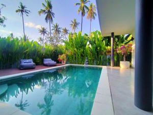 a swimming pool in a house with palm trees at Villa Ataya in Lovina