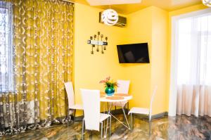 a dining room with yellow walls and a table and chairs at Kapitan Apartments in Odesa