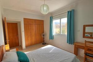 een slaapkamer met een bed en een raam met blauwe gordijnen bij Peyia Resort Apartment in Peyia +45 foto's