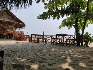 a beach with wooden tables and a straw hut at Shalom Beach Residency in Alleppey