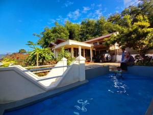 a woman sitting in front of a house with a pool at Bamboosa in Bukittinggi