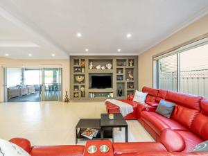 a living room with a red couch and a tv at Gather at Vincentia in Vincentia