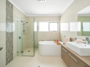 a bathroom with a tub and a sink and a shower at Gather at Vincentia in Vincentia +31 photos