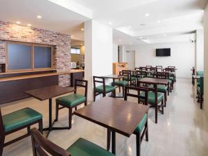 un restaurant avec des tables en bois et des sièges verts dans l'établissement Comfort Inn Ogaki, à Ōgaki