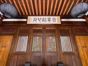 een houten deur met een bord erboven en ramen bij 金門古寧歇心苑官宅古厝民宿 Guning Xiexinyuan Historical Inn in Jinning