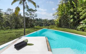 a pool in front of a villa with a black object on a table at Eco Six Bali in Tampaksiring