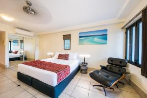 a bedroom with a bed and a chair at at Waterfront Whitsunday Retreat - Adults Only in Airlie Beach