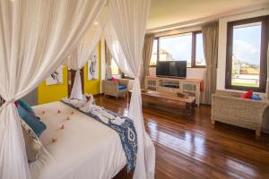 a bedroom with a bed with white curtains and a tv at Villa Padi Karo in Canggu