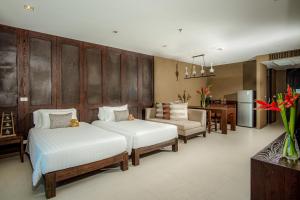 a bedroom with two beds and a table and a kitchen at Sunsuri Phuket - SHA Plus in Nai Harn Beach