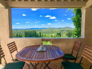 einen Holztisch und Stühle auf einer Veranda mit Aussicht in der Unterkunft Petit Paradis Bellevue in Montpezat