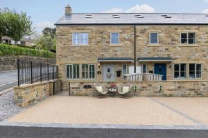 a stone house with two chairs and a table in front of it at Hilltop Snug cosy family home in bustling town of Pateley Bridge in the Yorkshire Dales - Book the combination of rooms and bathrooms you need 1-4 Bedrooms, 2 Bathrooms in Pateley Bridge