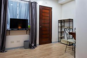 Zimmer mit einer Tür, einem TV und einem Stuhl in der Unterkunft Luis miguel's place in Dumaguete